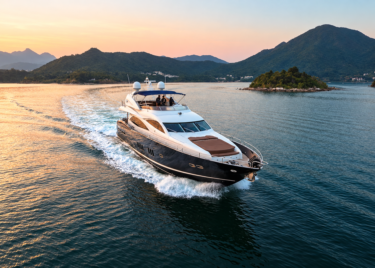 Motor yacht cruising past mountainous islands at sunset
